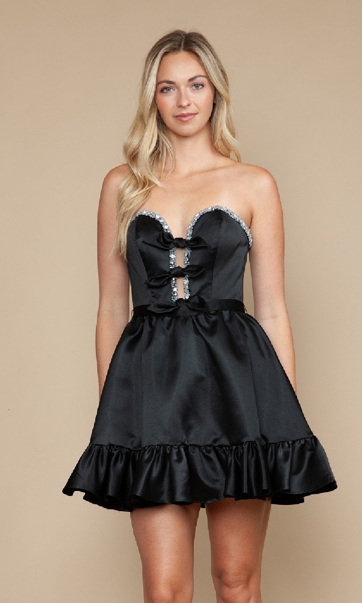 A woman models the Poly USA 9782, a ruffled strapless short black satin homecoming dress with rhinestone trim, against a beige background.